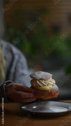 Vertical video of woman eating fresh pastry, a semla, in Sweden on Fat Tuesday. Sweet food and bake. Closeup on the pastry.