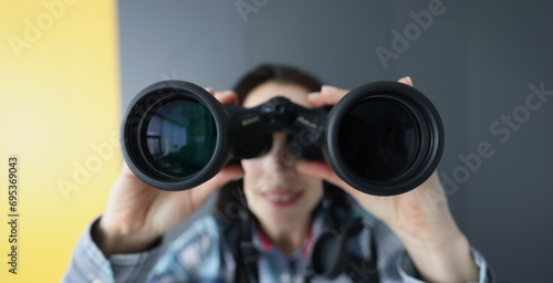 Young woman looking through black professional binoculars closeup. Baby tracking mobile apps concept