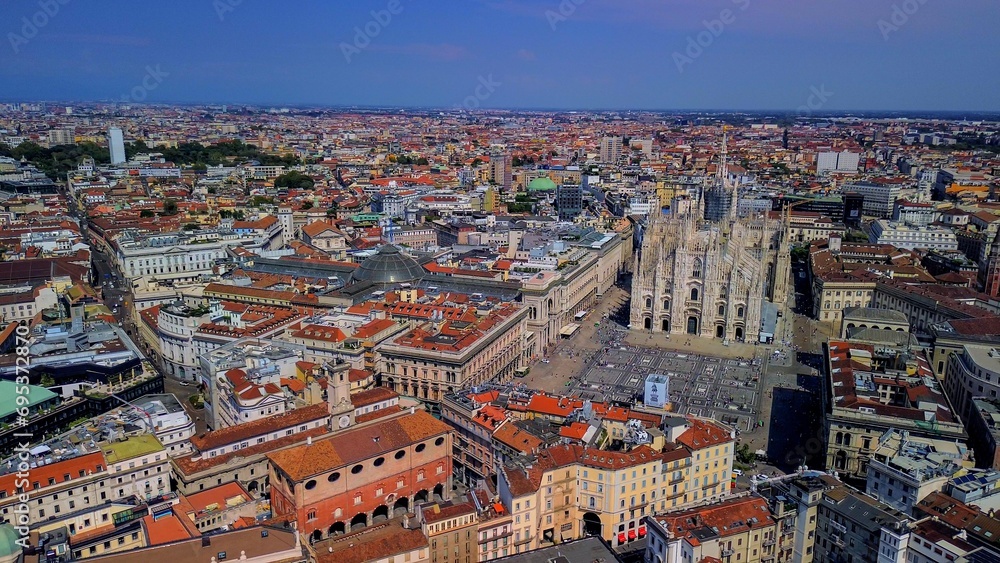 Aerial view of Piazza Duomo in front of the gothic cathedral in the center. Drone view of the gallery and rooftops during the day. Flight over the city. People in the city. Milan. Italy 15.12.2023