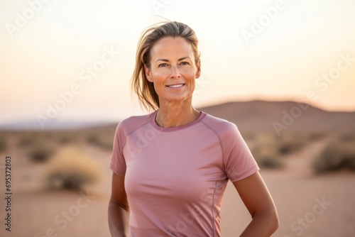 Portrait of a blissful woman in her 40s wearing a moisture-wicking running shirt against a backdrop of desert dunes. AI Generation
