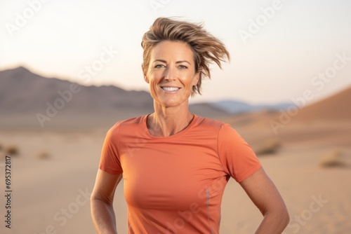 Portrait of a blissful woman in her 40s wearing a moisture-wicking running shirt against a backdrop of desert dunes. AI Generation