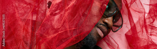 portrait of young african american man with red tulle fabric lying on floor, fashion concept, banner