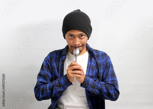 Photography Funny young Asian man, sporting a beanie hat and casual shirt, playfully holds a