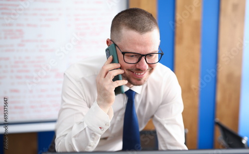 Portrait of smiling person talking on mobile phone and decide important question. Happy cheerful adult in stylish white costume. Career and business growth concept