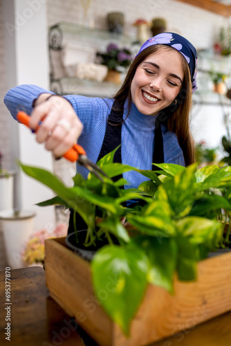Smiling woman trimming potted plant in floristry photo