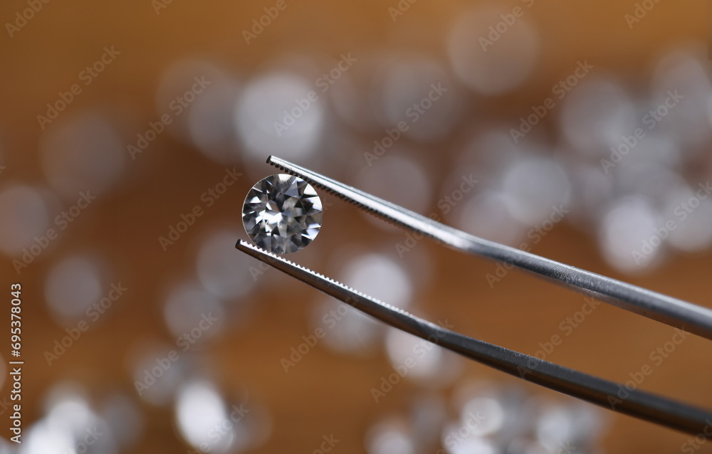 Close-up of bright shining crystal. Macro shot of fancy round shaped white diamond in workers tweezers. Carat size. Jeweler checking polished brilliant. Precious stone concept Close-up of bright shining crystal. Macro shot of fancy round shaped white diamond in workers tweezers. Carat size. Jeweler checking polished brilliant. Precious stone concept