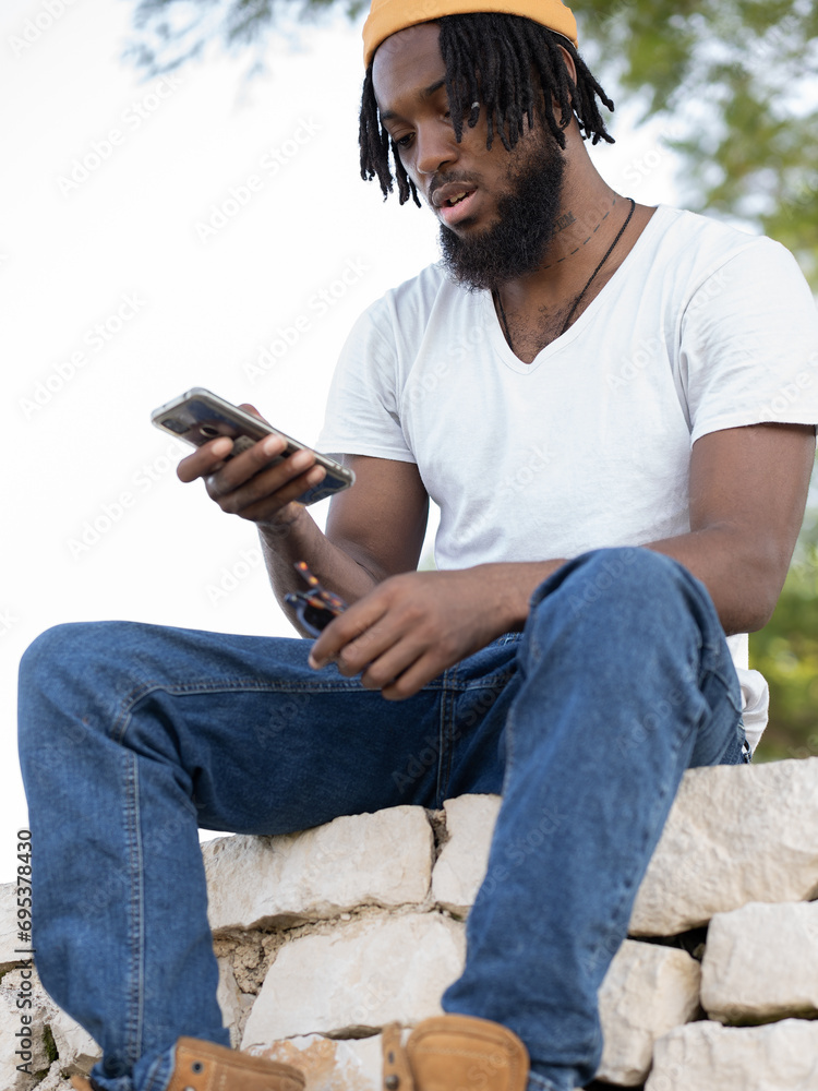Black man messaging on smartphone in park Black man messaging on smartphone in park
