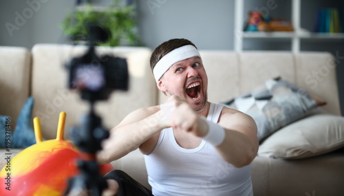 Screaming Vlogger Recording Boxing Video on Camera. Bearded Man Shooting Workout on Digital Camcorder for Fitness and Aerobic Vlog. Sportsman Doing Warmup Exercise for Hands Indoor Photography