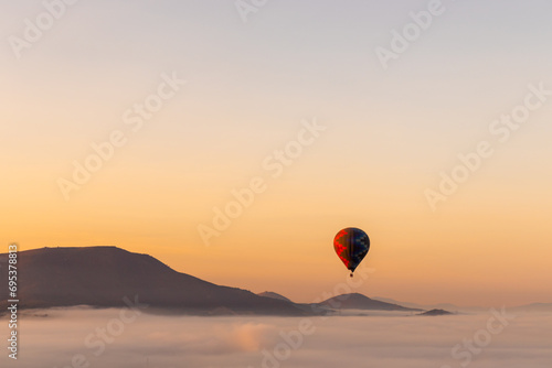Hot air balloon floating over pyramids at sunset photo