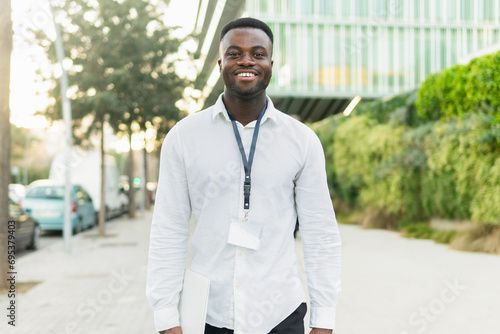 Smiling black businessman walking with laptop photo