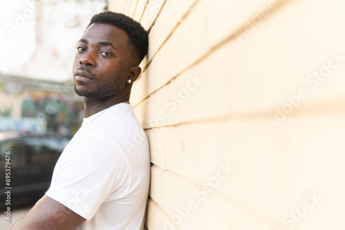 Black man leaning on wall of building photo