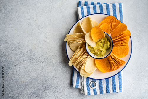 Assorted crisps with guacamole in concrete background photo