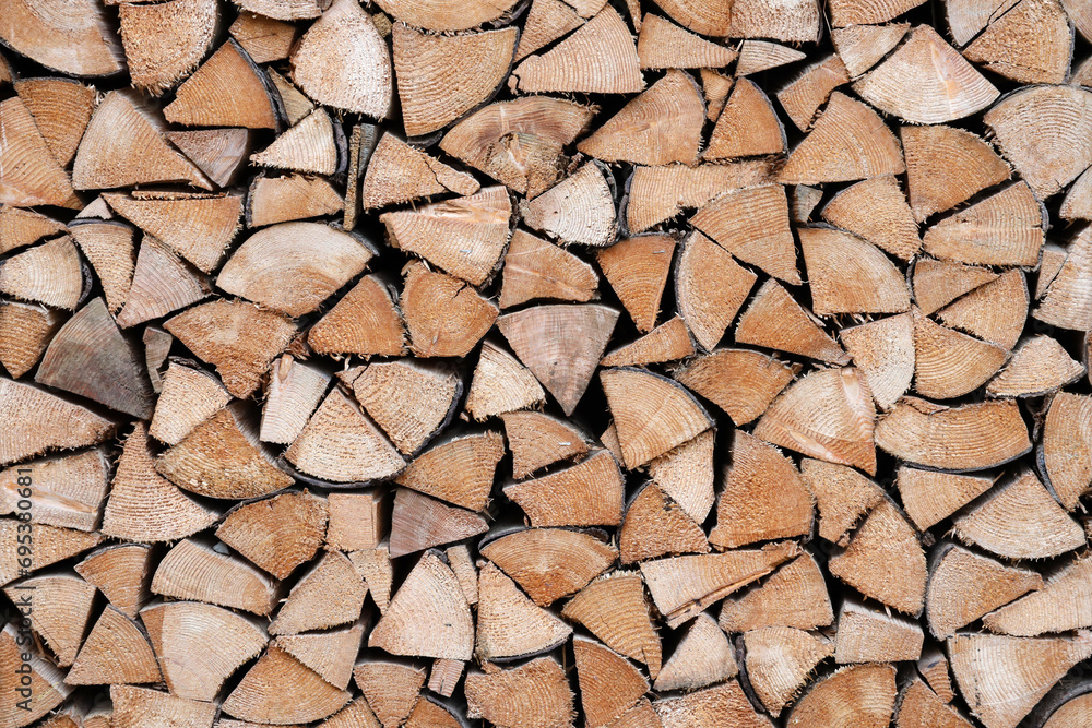 Firewood stacked near the wooden wall of old hut. Many chopped logs of firewood close up Firewood stacked near the wooden wall of old hut. Many chopped logs of firewood close up