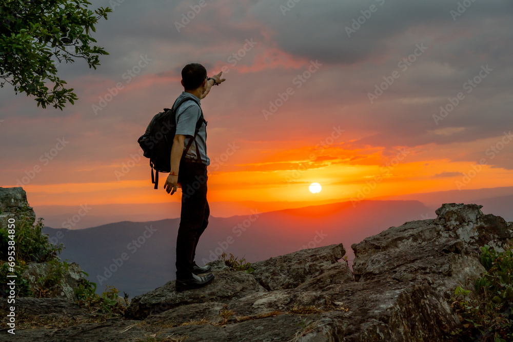 Alone man travel and sitting on cliff of hill and see view of sunset sky background