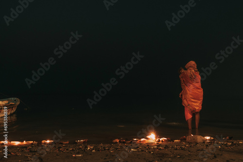 Sadu in orange clothes on the pre-dawn sacred river Ganges in Varanasi, India