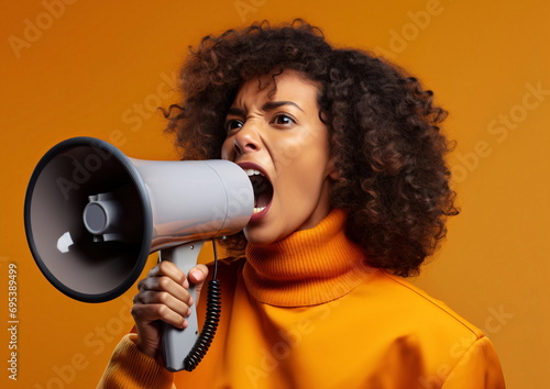 Woman shouting while holding a megaphone against yellow background
