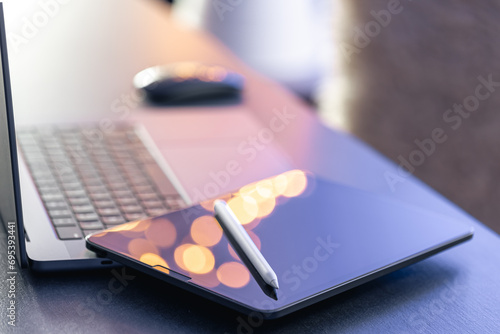 Digital tablet, stylus pen and laptop on the desktop, close up.