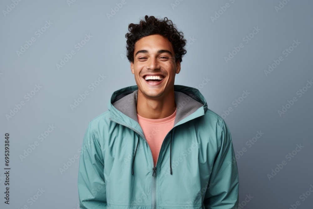 Portrait of a grinning man in his 20s wearing a lightweight packable anorak against a pastel gray background. AI Generation Portrait of a grinning man in his 20s wearing a lightweight packable anorak against a pastel gray background. AI Generation