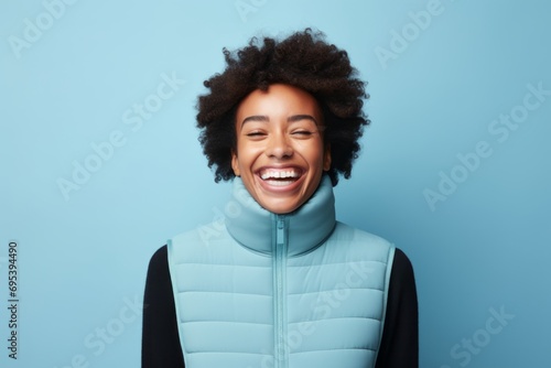 Portrait of a joyful woman in her 20s dressed in a thermal insulation vest against a soft blue background. AI Generation photo