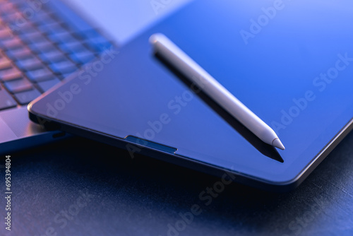 Digital tablet, stylus pen and laptop on the desktop, close up. photo