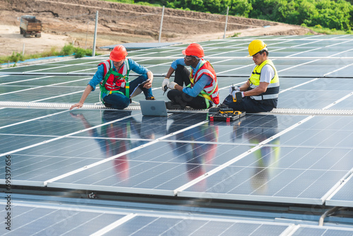 Professional technicians carrying photovoltaic solar moduls on factory roof, Engineers in helmets installing solar panel system outdoors. Concept of alternative and sustainable renewable energy.