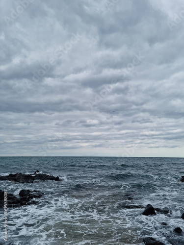 The rough sea of       Jeju is covered in dark clouds.