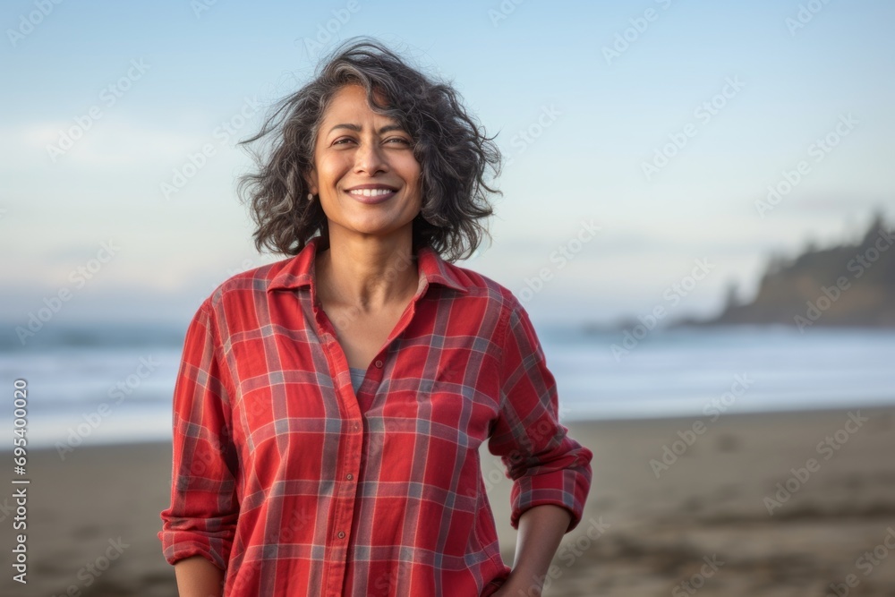 Portrait of a satisfied indian woman in her 50s wearing a comfy flannel shirt against a serene seaside background. AI Generation Portrait of a satisfied indian woman in her 50s wearing a comfy flannel shirt against a serene seaside background. AI Generation