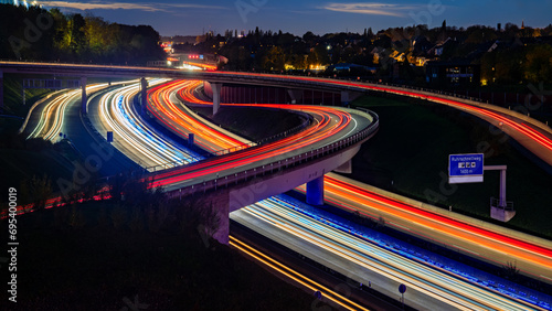 Panorama of motorway „Autobahn“  in Ruhr Basin Germany at evening twilight with bridges, curves and paralles lanes. Red and white light traces of passing cars and blue flash lights of emergency. photo