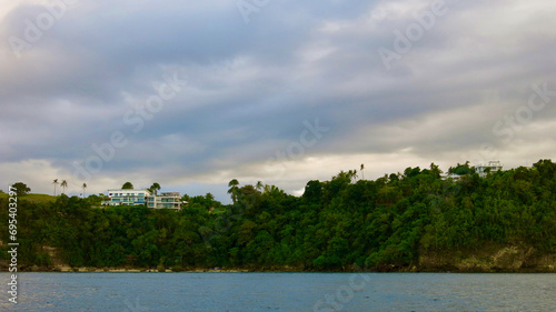 Clouds over a tropical island during sunset. The shore of a tropical island covered with jungle on a cloudy day at sunset.