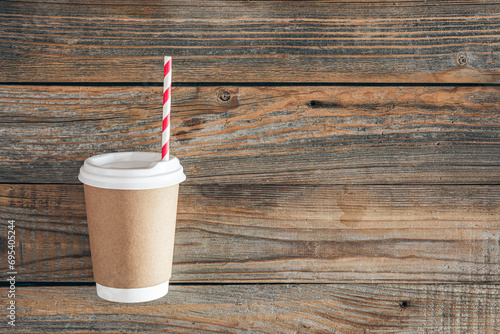 Paper cup and straw for drinks on a wooden background. photo