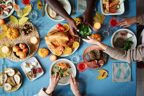People sharing dinner at fully arranger thanksgiving table full of festive dishes