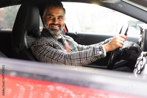 Smiling Indian man driving car while looking away photo