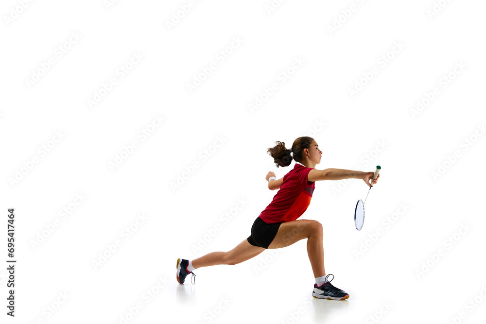 Dynamic portrait capturing athleticism of young, attractive female badminton player in motion during training against pristine white background. Concept of sport, strength and power, action. Dynamic portrait capturing athleticism of young, attractive female badminton player in motion during training against pristine white background. Concept of sport, strength and power, action.