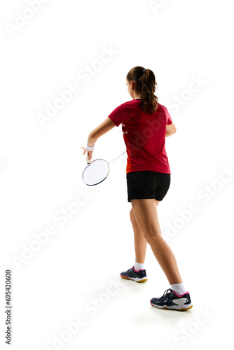 Rear view portrait of young girl, skilled badminton player practicing with intensity against pristine white background. Concept of sport, active lifestyle, strength and power, action. Copy space. © Lustre