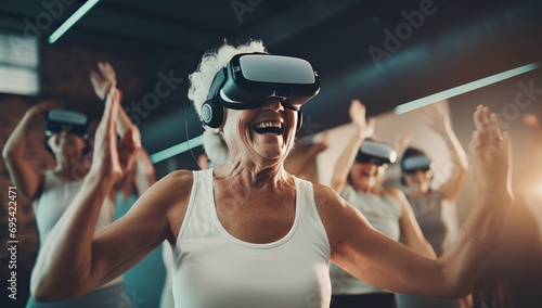 An excited elderly woman with a virtual reality headset on her head, raises her hands in the air in a room with other people. The concept of activity of the elderly photo