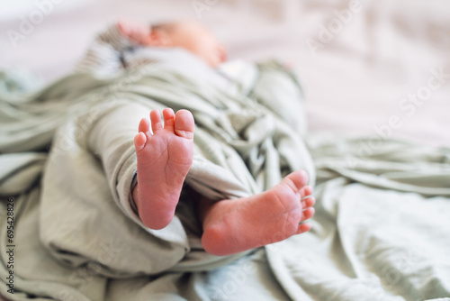 Close-up cute tiny newborn baby feet in soft green blanket wrap. photo