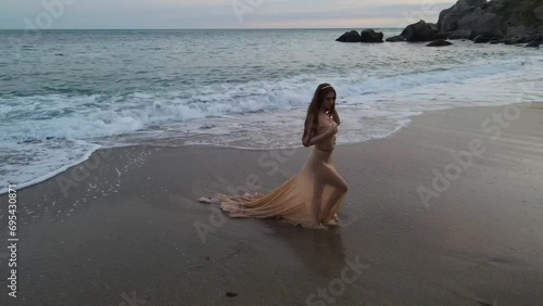 Young beautiful woman fallen angel stands on sea beach enjoy nature. costume bird white wings.