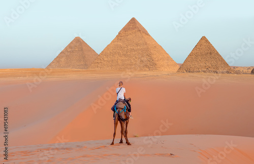 Camels in Giza Pyramid Complex - A woman riding a camel across the thin sand dunes - Cairo  Egypt