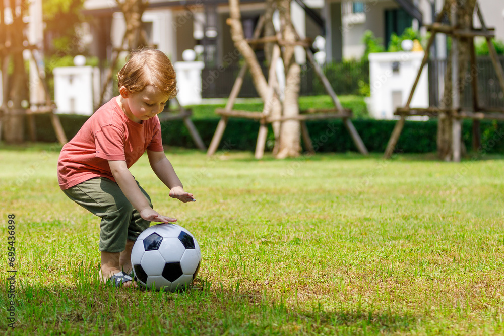 My son enjoys playing football in the backyard. Happy little child in nature in the park My son enjoys playing football in the backyard. Happy little child in nature in the park