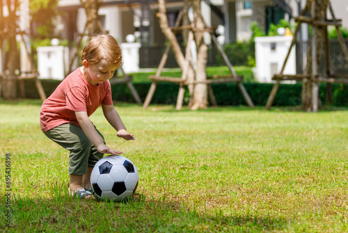 My son enjoys playing football in the backyard. Happy little child in nature in the park