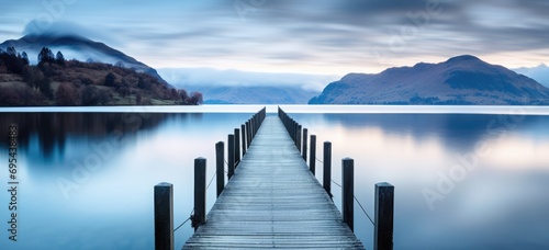 Tranquil lake pier leading into misty mountains at dawn. Serenity and nature. © Postproduction