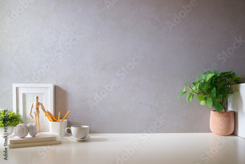 Creative designer workplace with picture frame mock up stationery and potted plant on white table. photo