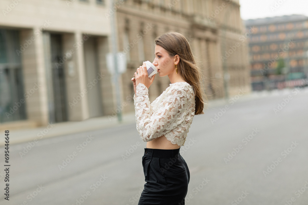 trendy young and pretty woman in lace top and high waist pants drinking coffee to go