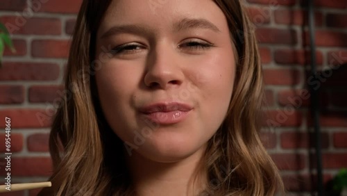 Close up shot of person eating different tasty food. Young girl slurping noodles inside mouth and smiling, happy face expression. POV.