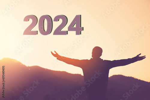 Man raise hand up on sunset sky at top of mountain and number 2024 abstract background..