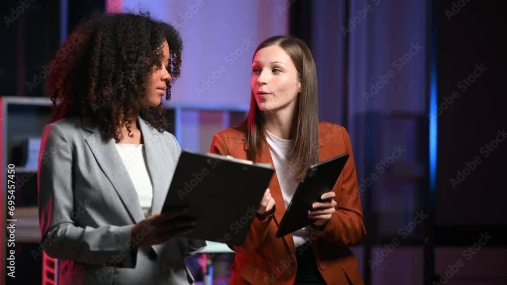 Kind leader executive manager share and discuss business solutions plan ideas on tablet with African female marketing manager in office. neon light Kind leader executive manager share and discuss business solutions plan ideas on tablet with African female marketing manager in office. neon light
