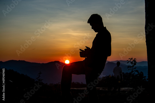 Fototapeta Naklejka Na Ścianę i Meble -  A man making a gesture of playing takraw in front of the setting sun