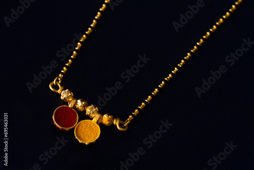 Still life image traditional Indian Hindu wedding necklace of  a bride called mangalsutra with Haldi and kumkum. Gold Mangalsutra. Indian Gold Jewellery.
 photo