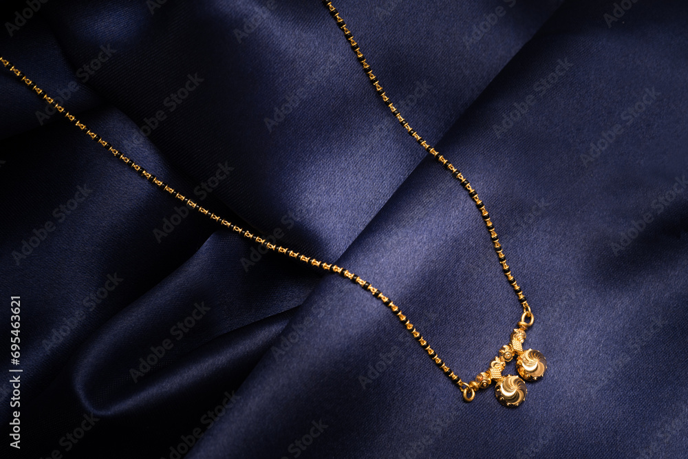 ndian traditional jewellery of a Hindu Married woman called as Mangalsutra or Muhurta mani on blue silk background. Creative jewellery product photography. ndian traditional jewellery of a Hindu Married woman called as Mangalsutra or Muhurta mani on blue silk background. Creative jewellery product photography.