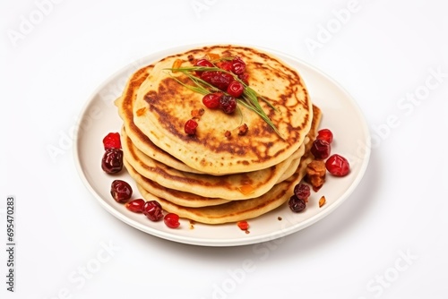  a stack of pancakes on a white plate with cranberries and a sprig of rosemary on top of the pancakes and cranberries on the plate.